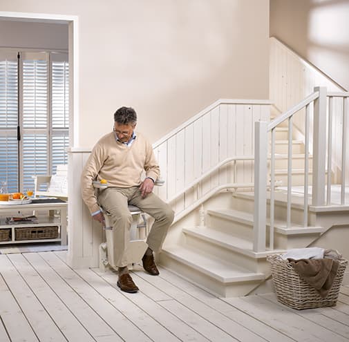 A man sitting on Otolift Two Stairlit - Breffni Mobility | The Stairlift Specialists